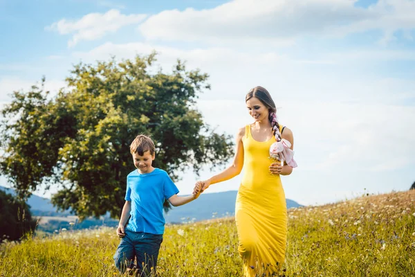 Mutter läuft mit ihrem Sohn auf einer Sommerwiese — Stockfoto