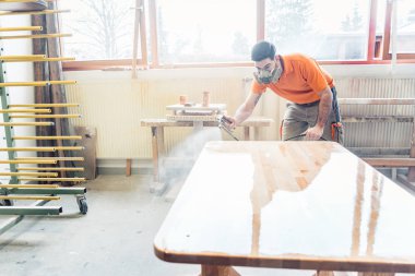 üzerinde çalıştığı bir tabloda vernik püskürtme marangoz adam