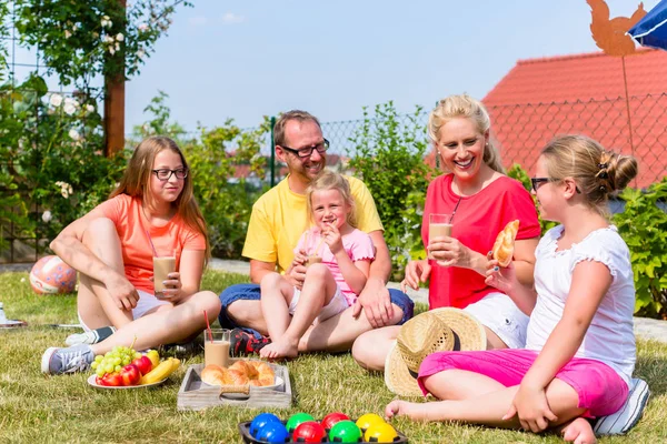 Famiglia che fa un picnic in giardino di fronte alla loro casa — Foto Stock