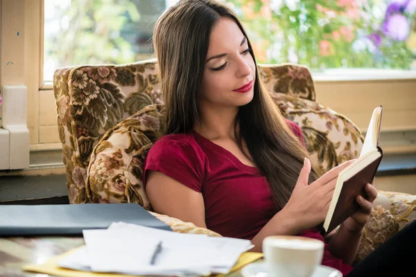 Avslappnad ung kvinna läsa en bok inomhus — Stockfoto