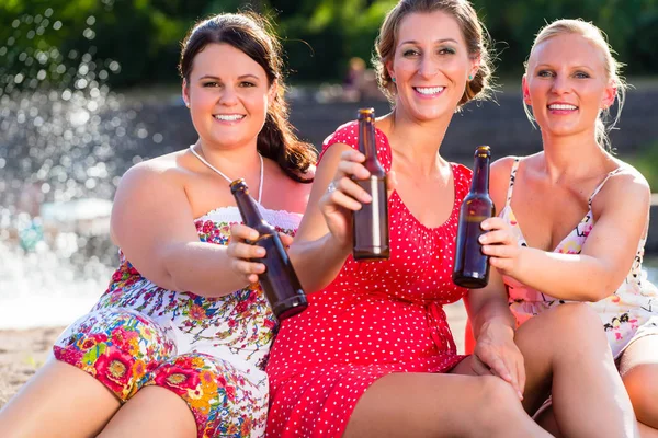 Vänner som dricker öl på river beach — Stockfoto