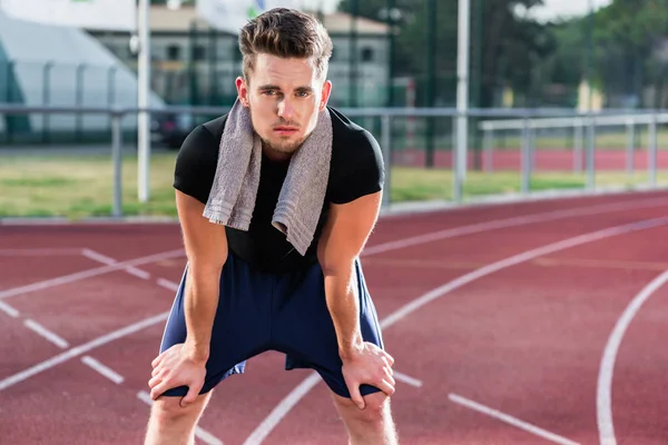 Athlete stretching on racing track before running — Stock Photo, Image