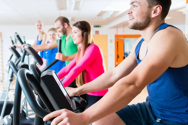 Homens e mulheres em bicicletas de cardio no ginásio — Fotografia de Stock