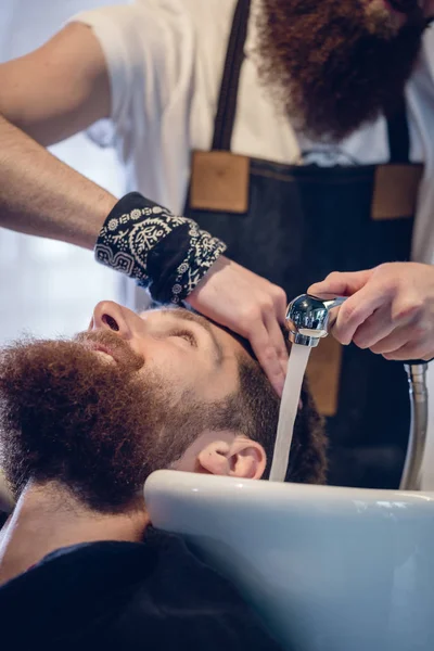 Primer plano de las manos de un peluquero experto que da un lavado de pelo al cliente —  Fotos de Stock