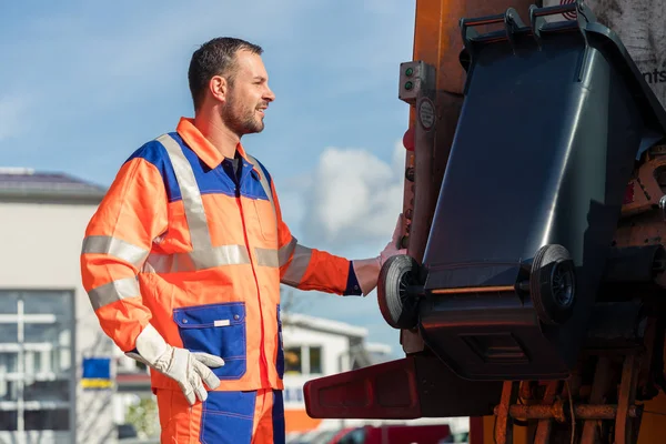 Garbage collection worker putting bin into waste truck — Stock Photo, Image