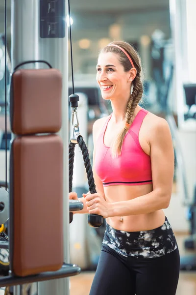 Mujer en forma feliz con sujetador rosa fitness mientras hace ejercicio en el gimnasio —  Fotos de Stock