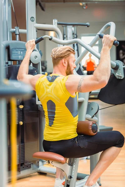 Visão traseira de um poderoso fisiculturista com fortes braços exercitando-se no ginásio — Fotografia de Stock