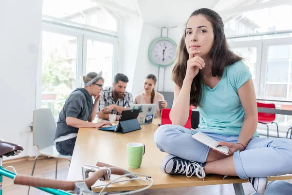 Hermosa joven sentada en un escritorio durante el trabajo —  Fotos de Stock