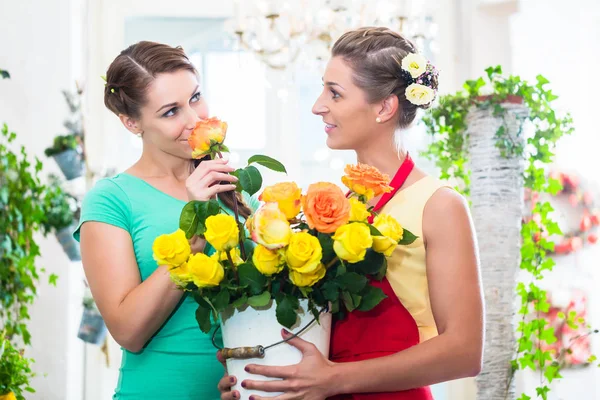 Mujeres en floristería disfrutando de las rosas — Foto de Stock