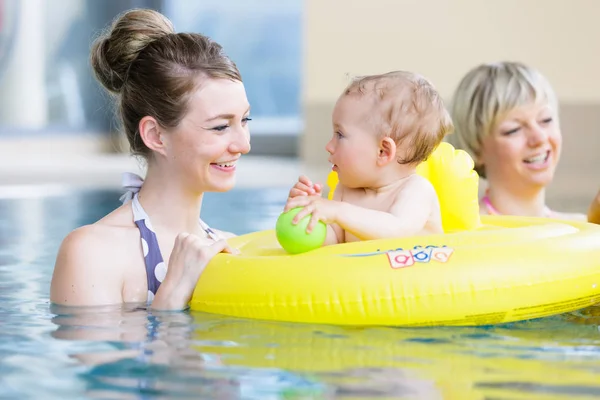 Madri e bambini si divertono insieme giocando con i giocattoli in piscina — Foto Stock