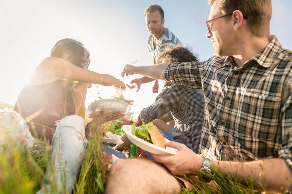 Amigos haciendo picnic en la barbacoa de verano y comiendo juntos —  Fotos de Stock