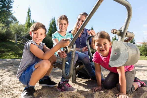 Madre e hijos en sandbox jugando con excavadora — Foto de Stock