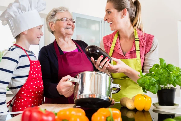 Abuela, mamá e hijo hablando mientras cocinan en la cocina — Foto de Stock