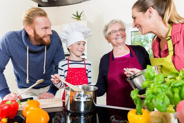 Mom, dad, granny and grandson together in kitchen preparing food — Stock Photo, Image