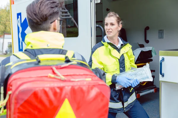 Ambulanspersonal framför ambulans diskuterar distribution — Stockfoto