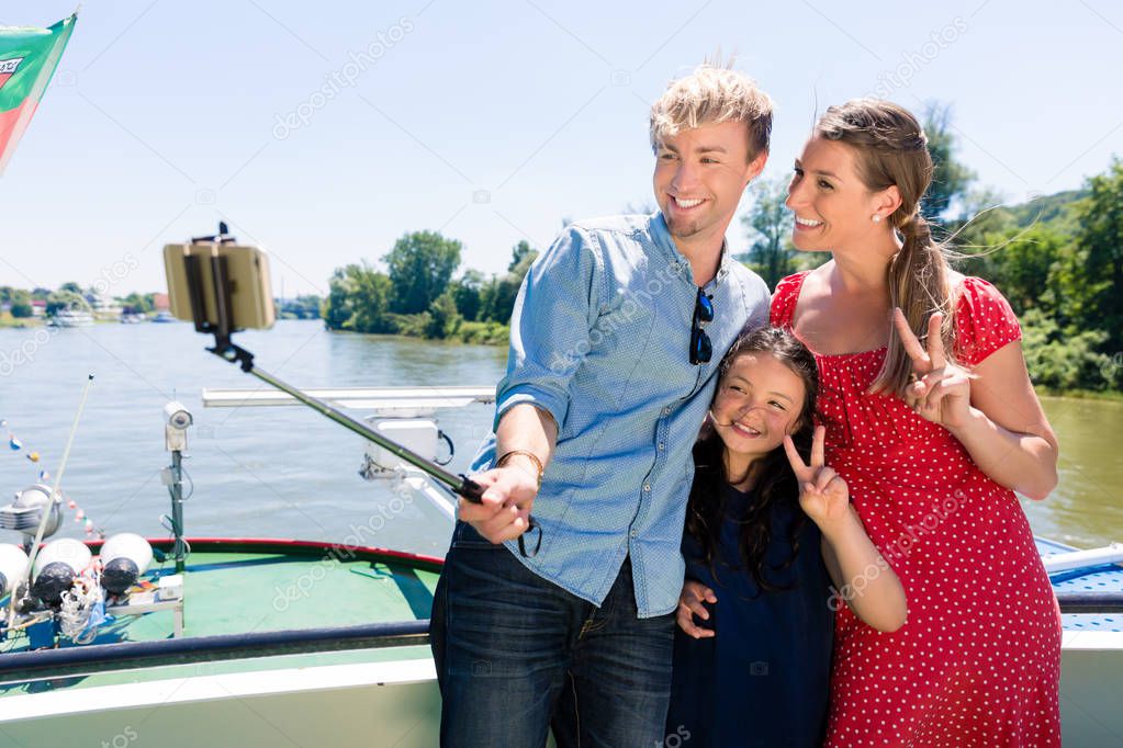 Family on river cruise with selfie stick in summer