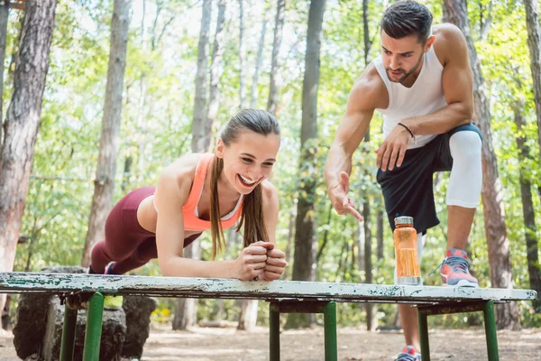 Hermosa mujer haciendo una tabla con el hombre mirando — Foto de Stock