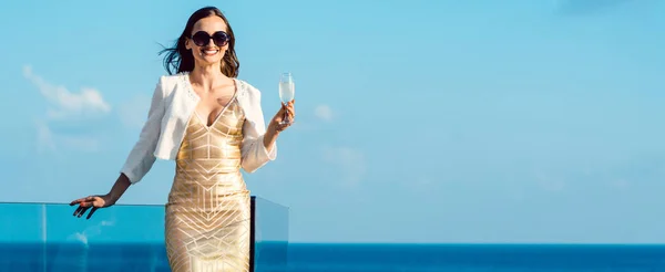 Kvinna som dricker mousserande vin tittar över havet — Stockfoto