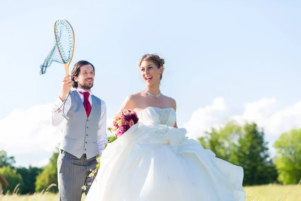 Свадебный жених ловит невесту с сеткой — стоковое фото