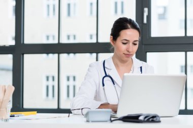 Ofiste dizüstü bilgisayar üzerinde çalışan genç kadın doktor portresi