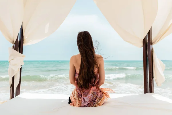 Mujer sentada en la cama de playa mirando al mar —  Fotos de Stock
