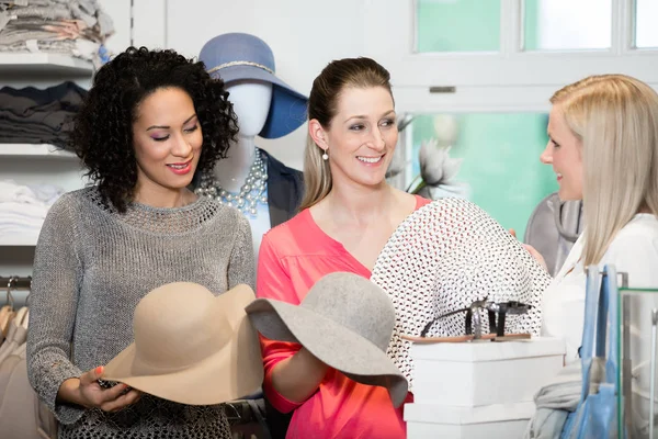 Girlfriends on shopping spree trying ladies hats — Stok Foto