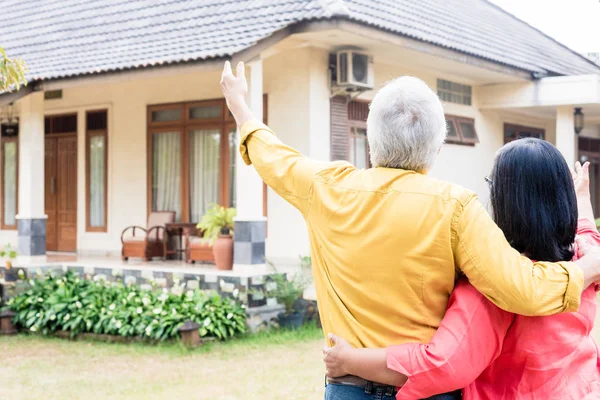 Homme âgé pointant vers sa femme une maison d'habitation confortable — Photo