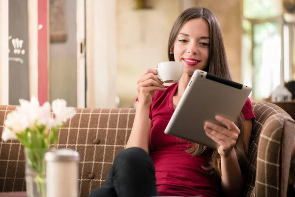Jovem contemporânea lendo no tablet em uma cafeteria — Fotografia de Stock