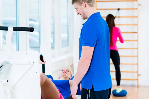 Homens e mulheres fazendo exercícios em diversos equipamentos no ginásio — Fotografia de Stock