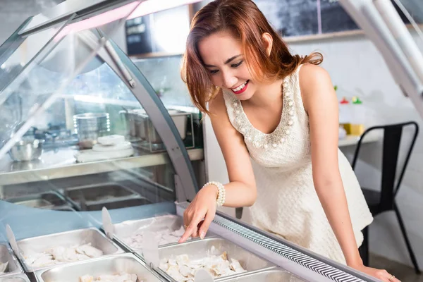 Mulher sorrindo selecionando comida de um balcão de deli — Fotografia de Stock