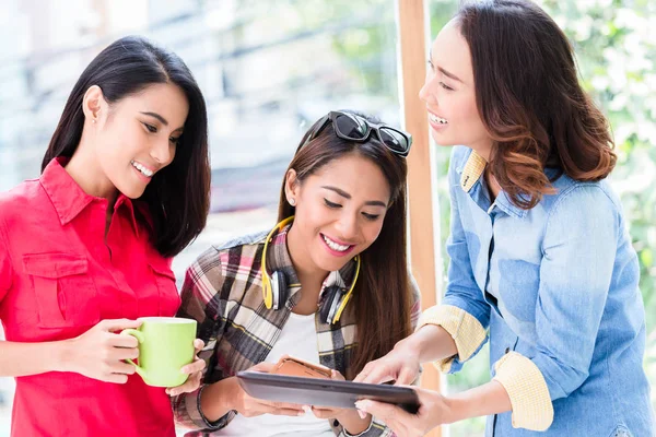 Tres mujeres jóvenes que se divierten mientras miran una tableta PC durante el descanso — Foto de Stock