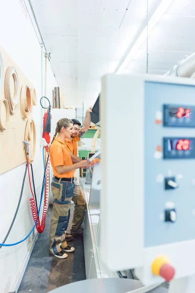 Two carpenters cleaning veneer machine in workshop — Stock Photo, Image