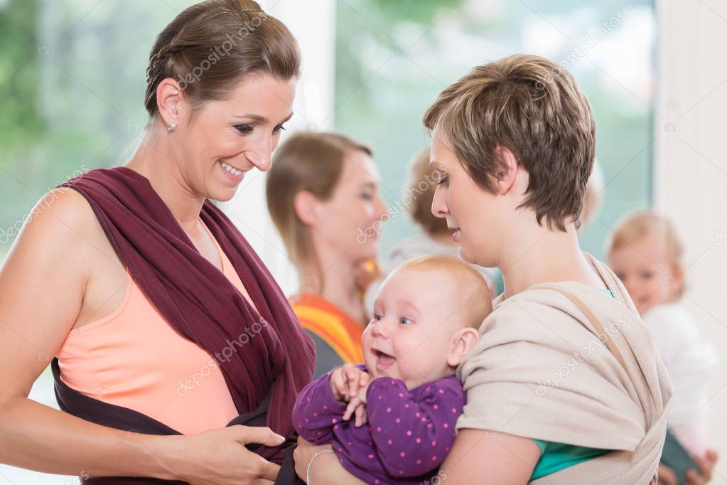 Young women learn how to use baby carriers for carrying children