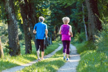 Tam uzunlukta dikiz üst düzey bir çiftin birlikte açık havada park pastoral bir yolda yaz aylarında koşu sırasında serin çalışan kıyafetler giyiyor 