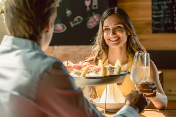 カキとカニのレストランでシーフードを使ったロマンチックなディナーにシャンパンと乾杯恋幸せな若いカップル — ストック写真