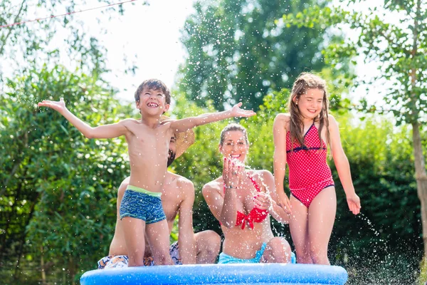 Refrigeración familiar salpicando agua en la piscina del jardín —  Fotos de Stock