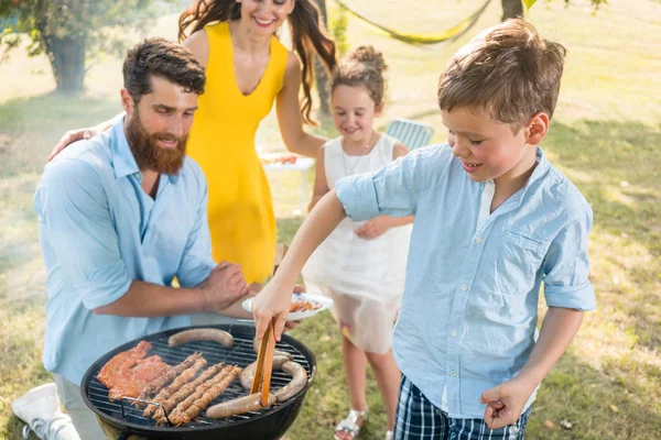 Otec a syn připravuje maso na gril na dřevěné uhlí gril během pikniku — Stock fotografie