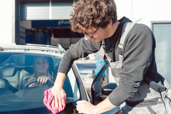 Diligente hombre de servicio ayudando a la mujer a limpiar su coche en lavado comercial — Foto de Stock