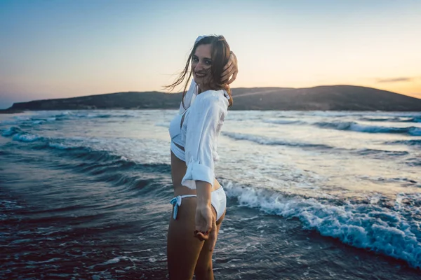 Mujer divirtiéndose en la playa durante la puesta del sol —  Fotos de Stock