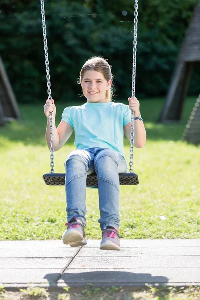 Kid having swingtime at adventure playground — Stock Photo, Image