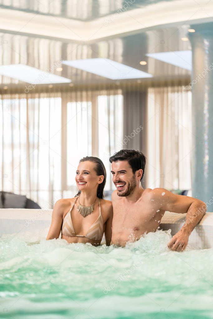 Young and happy couple in love relaxing in jacuzzi of spa or luxury hotel