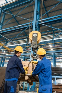İki işçi ağır yükleme Crane tarafından kaldırdı işleme