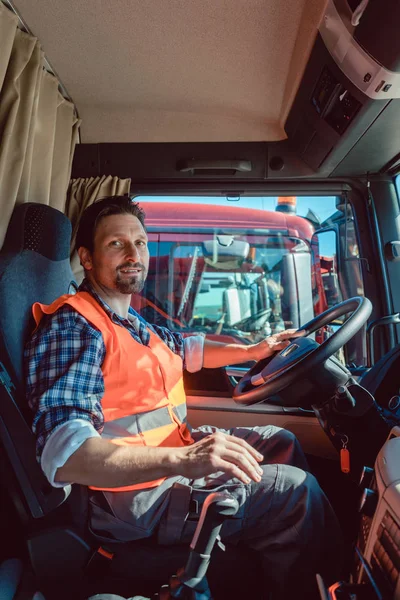 Vrachtwagen of vrachtwagen bestuurder zitten in de cabine van zijn voertuig — Stockfoto
