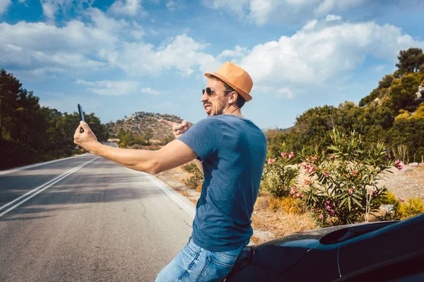 Turistické muž fotí selfie v jeho dovolené pomocí telefonu — Stock fotografie