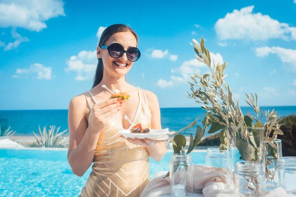 Kvinna i gyllene klänning att ha mat på stranden fest — Stockfoto