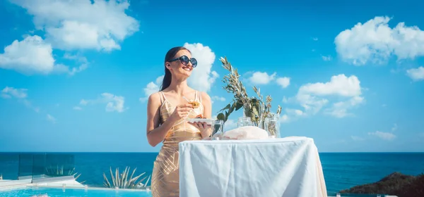 Kvinna i gyllene klänning att ha mat på stranden fest — Stockfoto