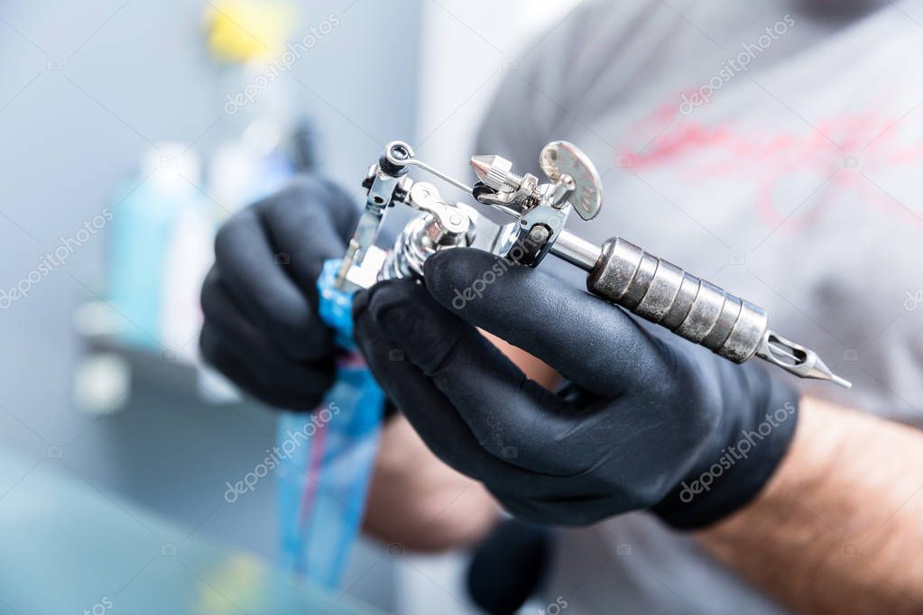 Close-up of the hands of a skilled tattoo artist wearing black gloves