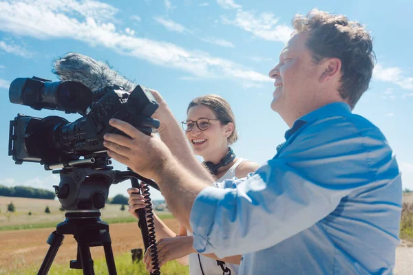 Cameraman met zijn camera en assistent werken in productie — Stockfoto