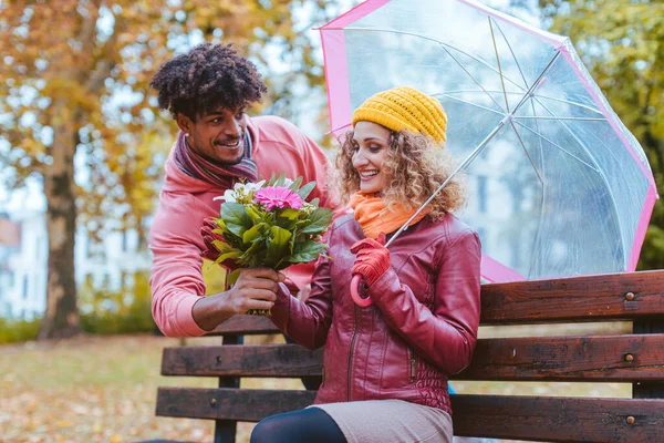 L'uomo sorprende sua moglie con un mazzo di fiori in un giorno di caduta piogge — Foto Stock