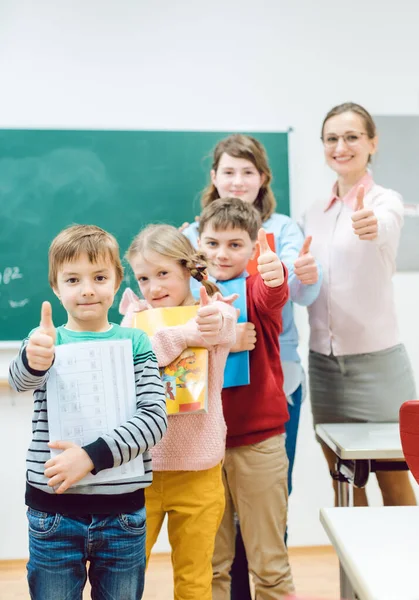 Uczniowie i nauczyciel pokazuje kciuki up w szkole, zabawy — Zdjęcie stockowe